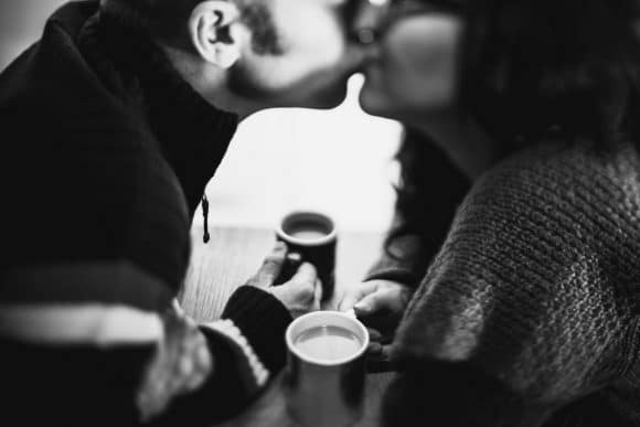 couple kissing over coffee